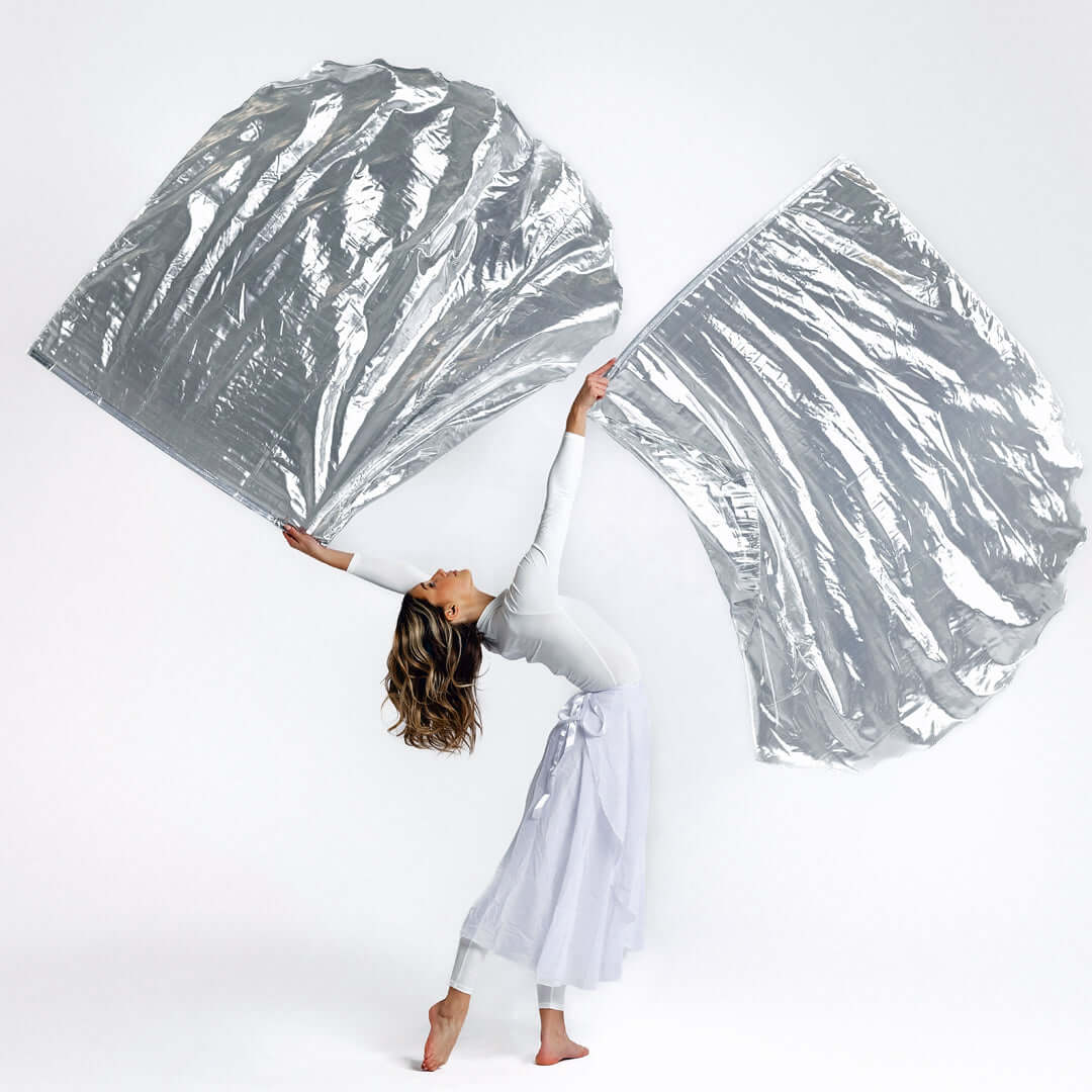 Worship dancer flowing with large silver metallic flags, symbolizing redemption, refinement, and the glory of the Lord.
