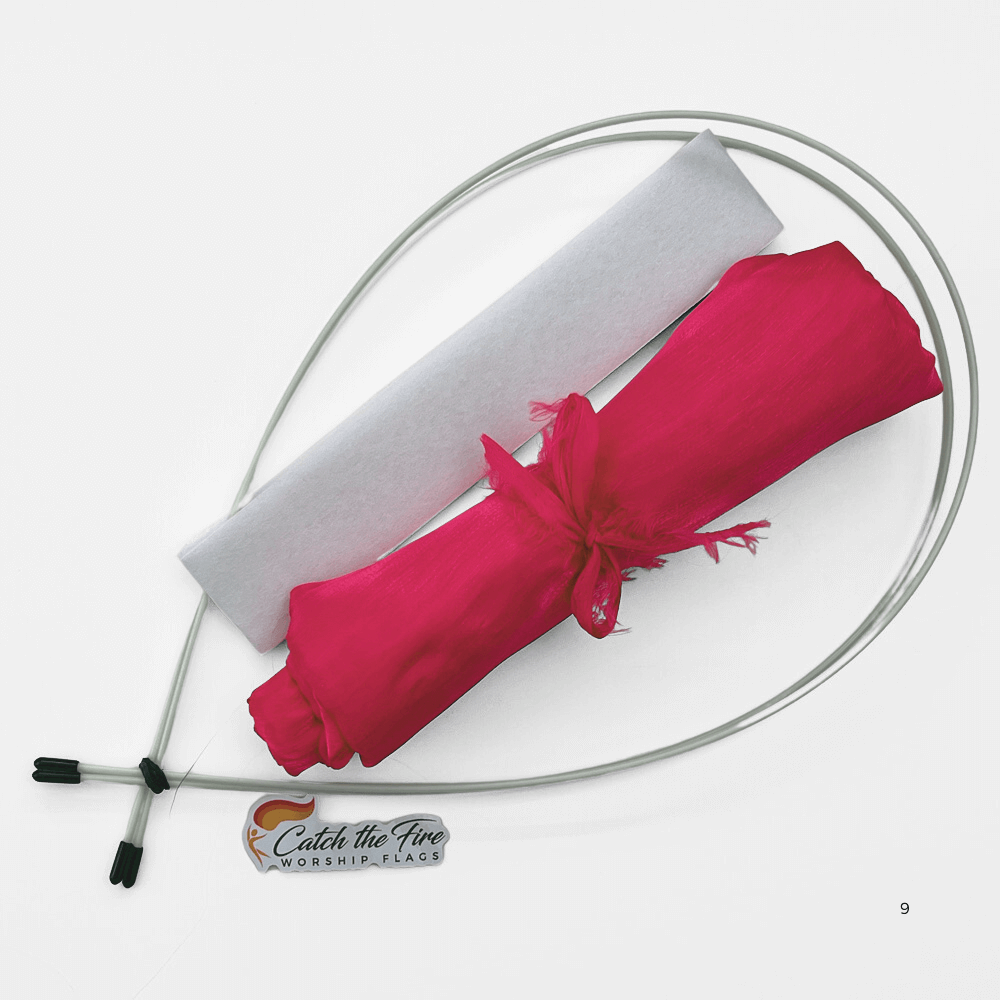 Worship flag travel kit featuring rolled pink flag fabric, two flexible travel rods, a white fabric sleeve, and Catch the Fire Worship Flags logo.