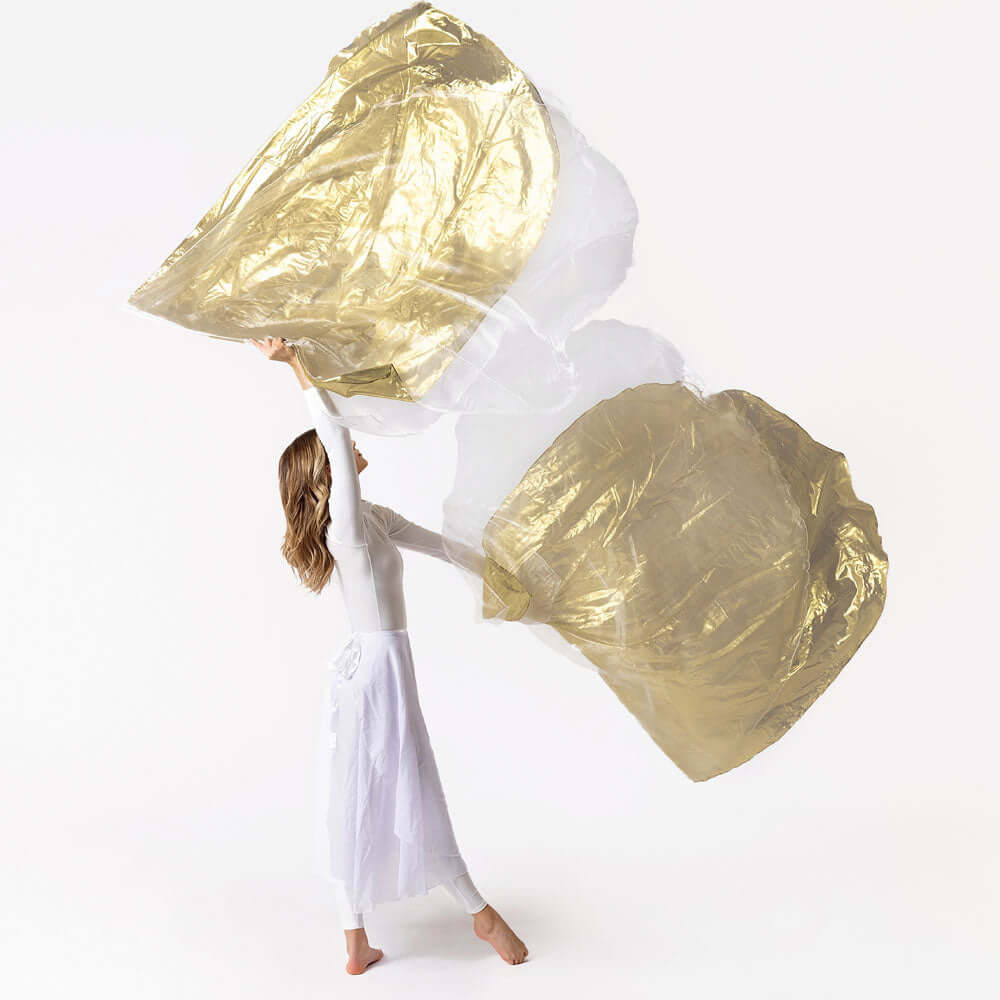 Worship dancer in white attire gracefully lifting large white and gold layered worship flags against a clean white background, showcasing movement and elegance.