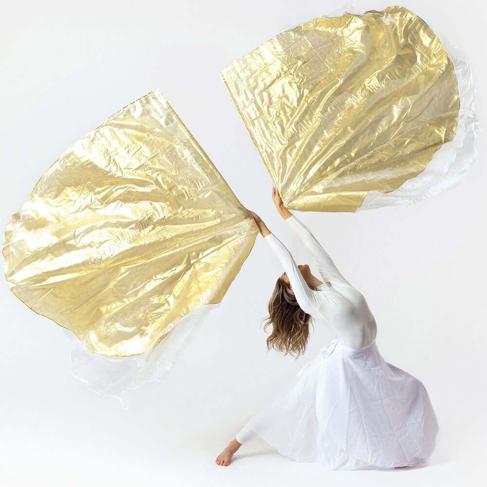 Worship dancer in flowing white attire performing with large white and gold prophetic worship flags in a graceful split pose against a white background.