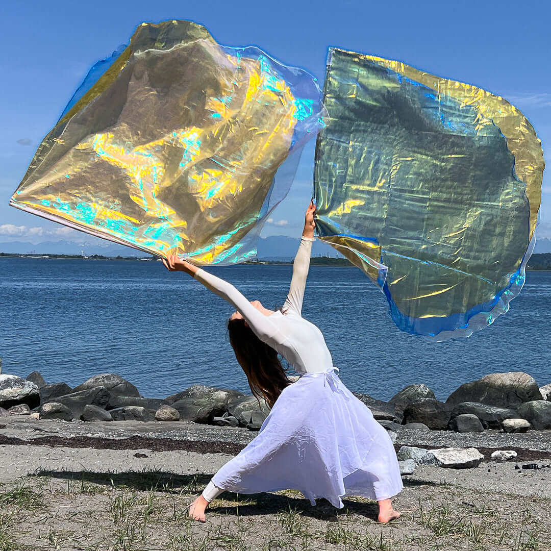A dancer flowing with shimmering worship flags by the water, symbolizing praise and prophetic movement in worship.