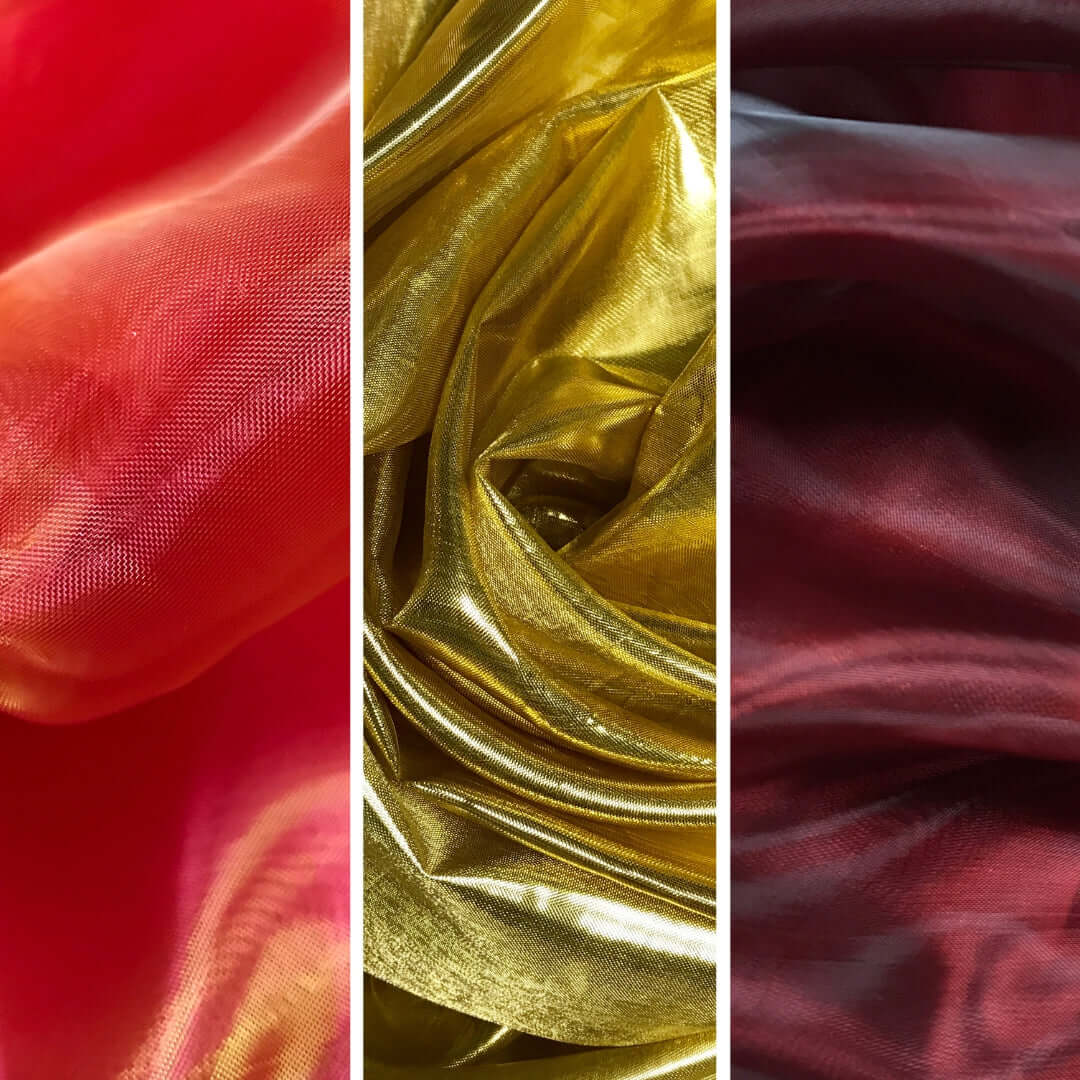 A close-up trio of vibrant worship flag fabrics. On the left, coral red fabric glows with warm undertones. In the center, metallic gold fabric shines with high reflectivity and rich texture. On the right, deep wine-colored fabric adds a moody, elegant contrast with subtle shimmer.