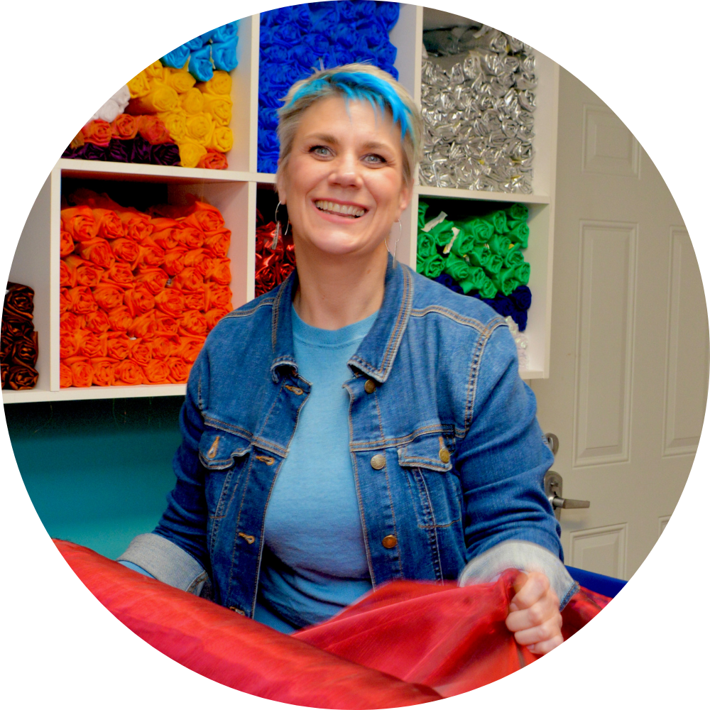 Andrea York, worship flag maker and founder of Catch the Fire Worship Flags, in her studio surrounded by vibrant worship flag fabrics.