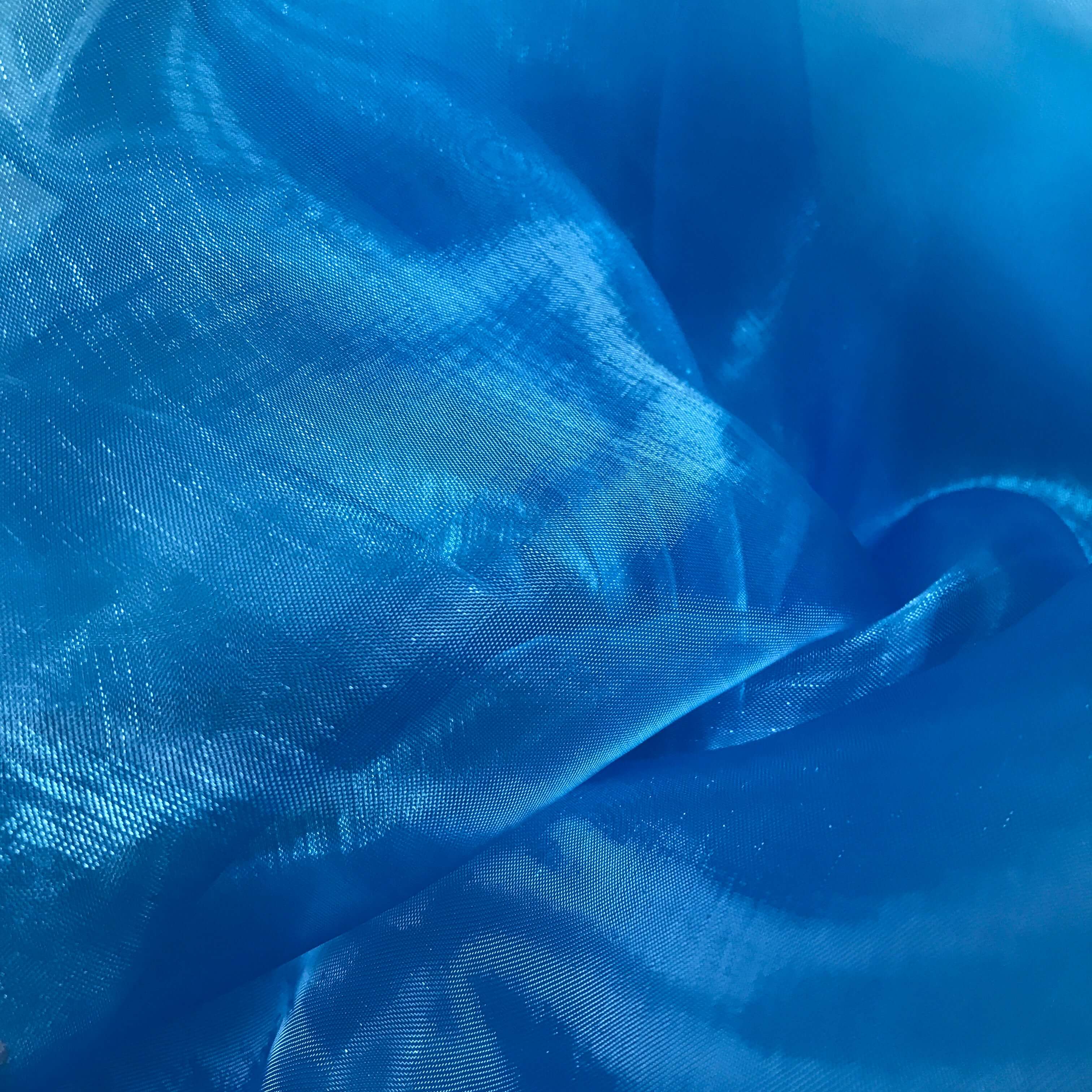 Close-up of shimmering blue iridescent fabric with soft folds and light-reflecting texture, ideal for use in worship flags or expressive dance garments.