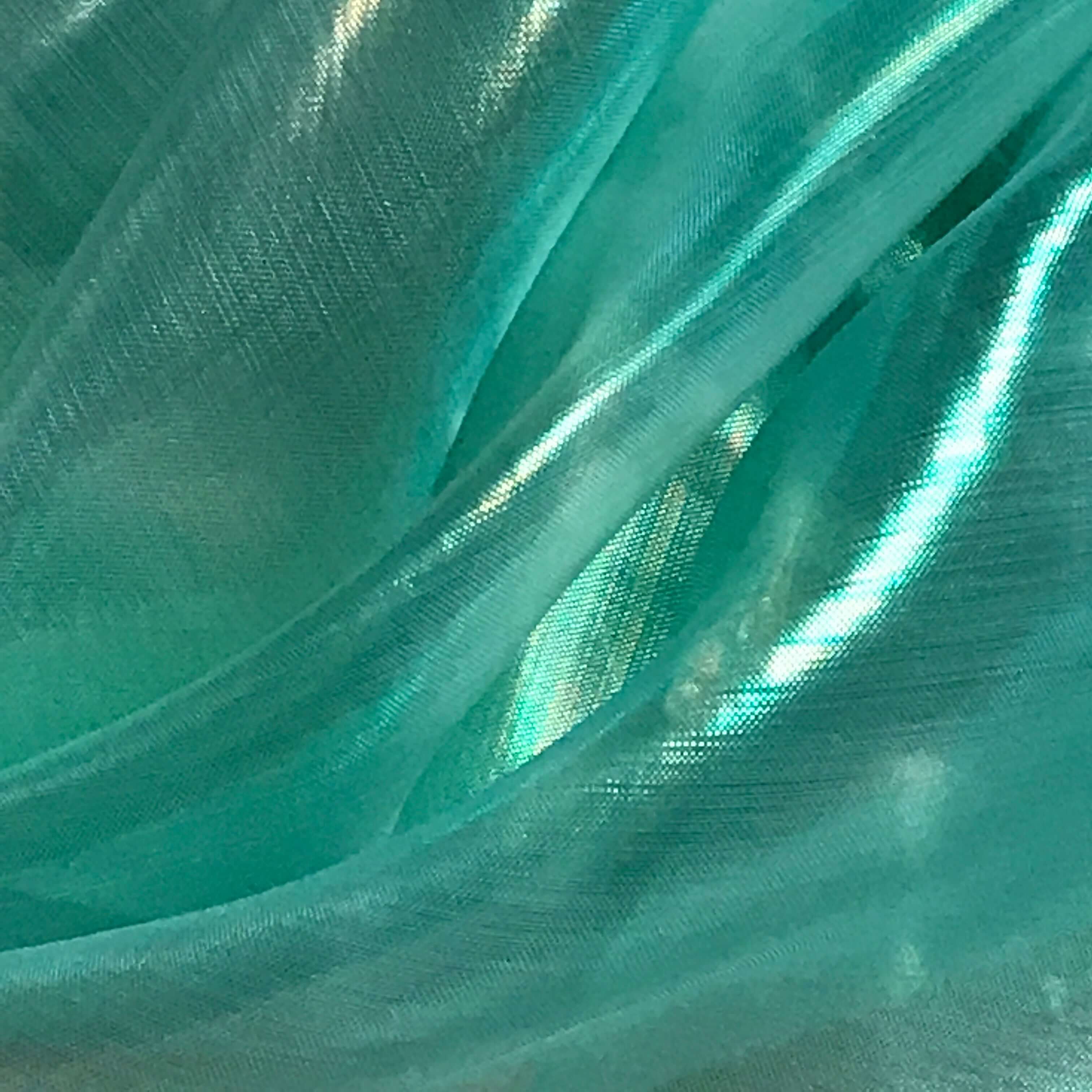 Close-up of iridescent seaglass green fabric with shimmering texture and light reflections, used in handcrafted worship flags for expressive praise movement.