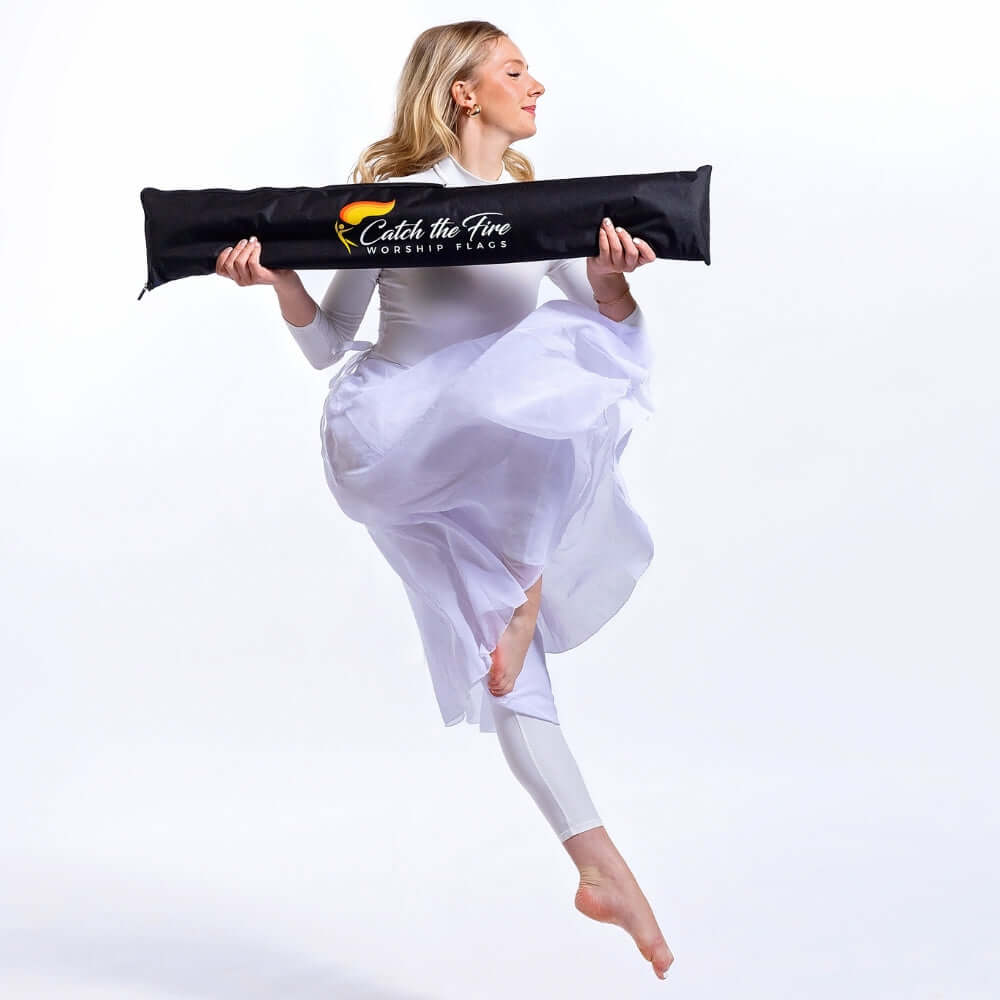 Praise dancer jumps holding Catch the Fire Worship Flags storage bag—black padded flag case for storing dance flags and flexion poles.