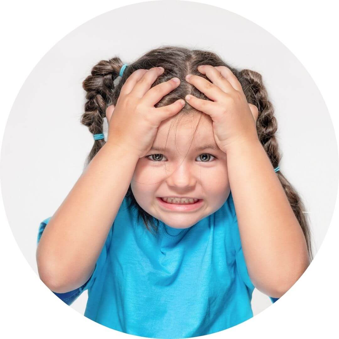 Frustrated young girl in blue shirt holding her head in distress, expressing disappointment or confusion.