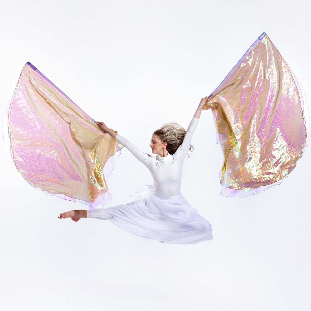 Praise dancer performs leap with Harp & Bowl shimmer flags – triple-layer design with gold, crystal, and lilac fabric symbolizing worship and intercession