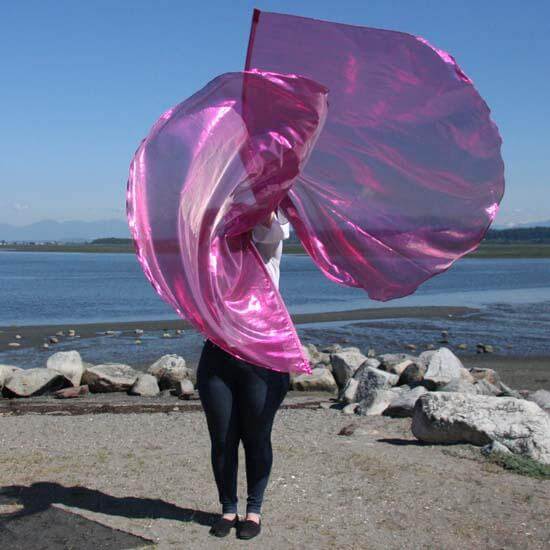 Worshipper on a rocky shoreline waving large scarlet worship flags with iridescent sheen, symbolizing extravagant love and spiritual joy in praise dance.