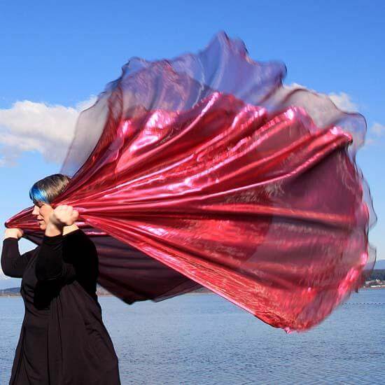 Worshipper with vibrant wine and scarlet metallic worship flag flowing in the wind near the water, symbolizing passionate praise and intercession.