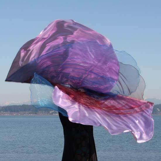 Worship flags in wine, pink, and blue flowing in motion against a coastal background, showcasing layered sheer fabrics with iridescent shimmer.