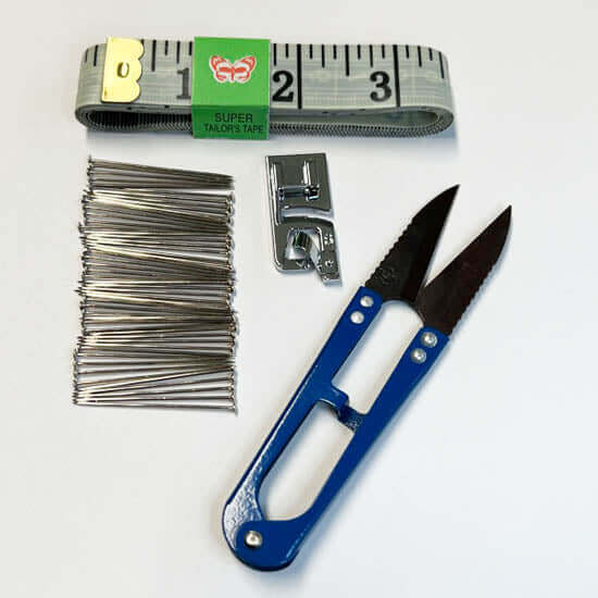 DIY worship flag sewing kit with measuring tape, dressmaker pins, universal rolled hem presser foot, and blue sewing scissors on white background.