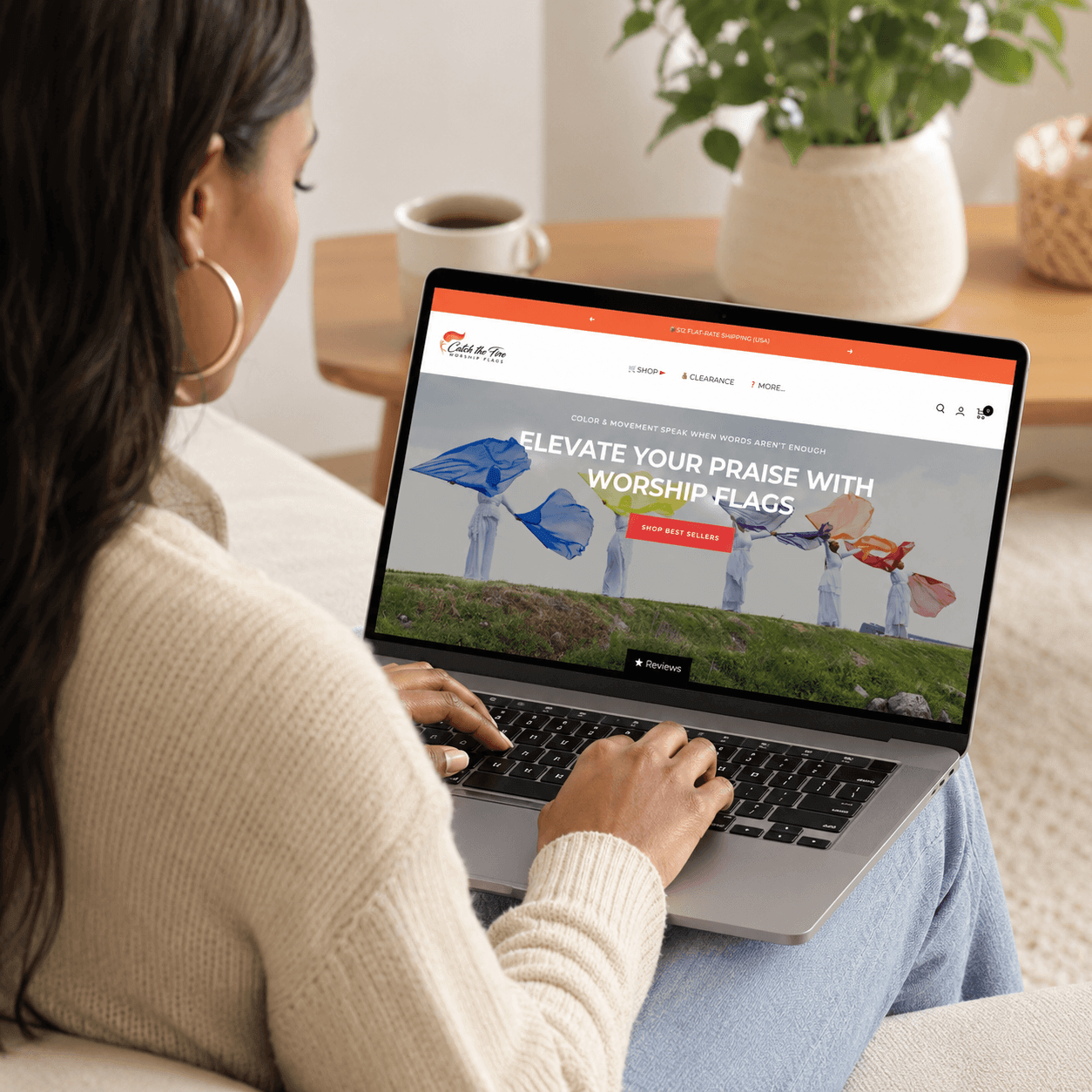 Woman shopping for worship flags online on a laptop while browsing the Catch the Fire Worship Flags website from home.