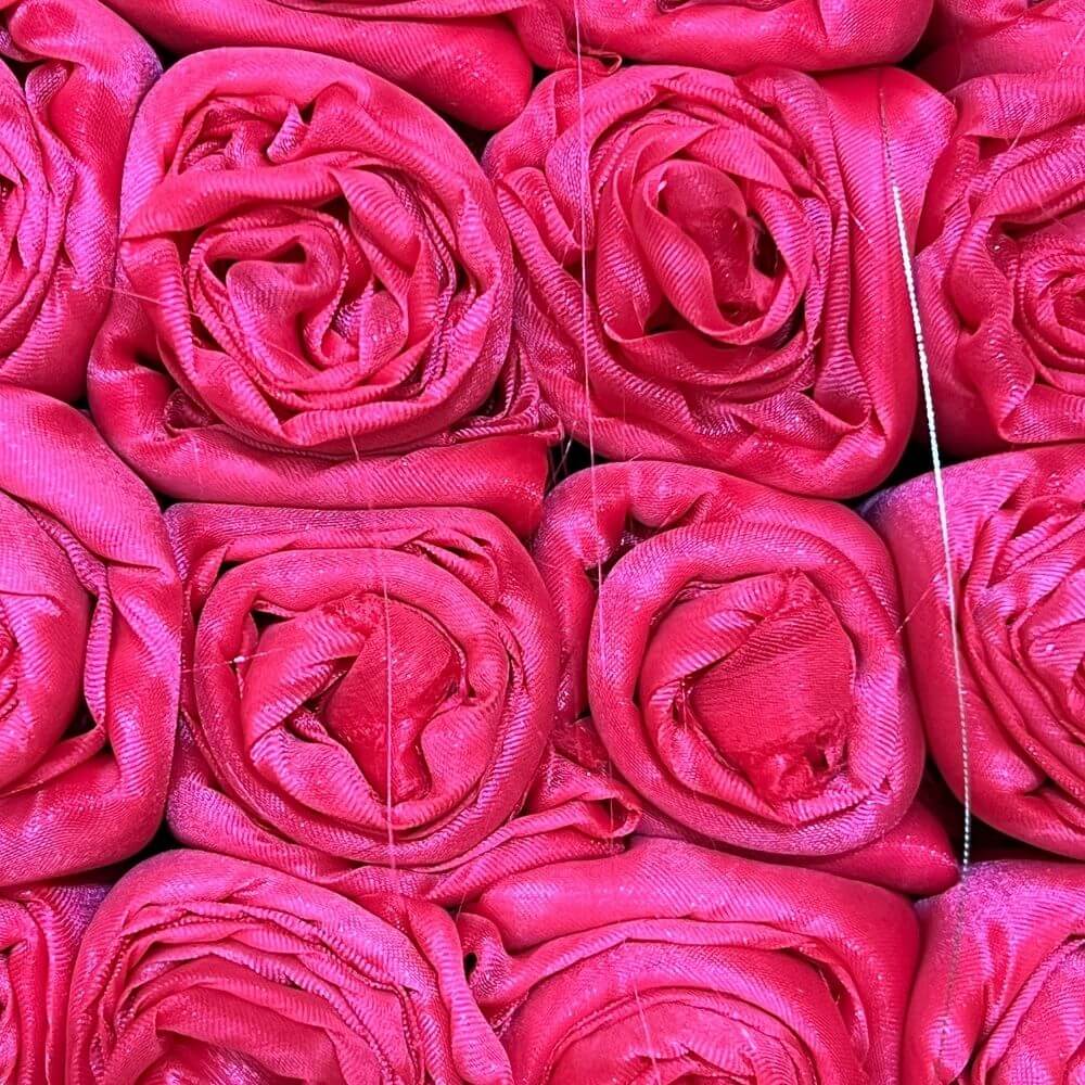 Close-up of scarlet shimmer worship flags rolled tightly and arranged in rows resembling blooming roses, with visible fabric sheen and thread lines.
