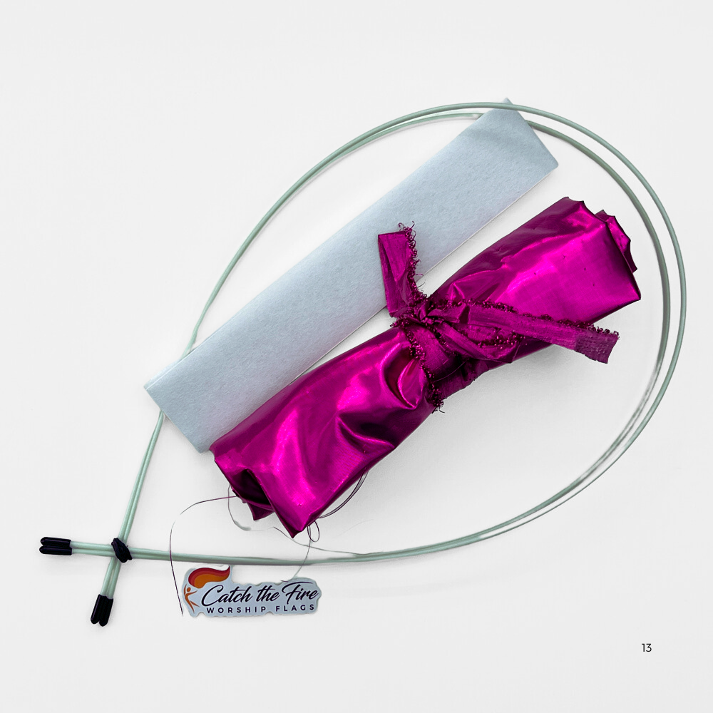 Worship flag travel kit featuring rolled pink flag fabric, two flexible travel rods, a white fabric sleeve, and Catch the Fire Worship Flags logo.