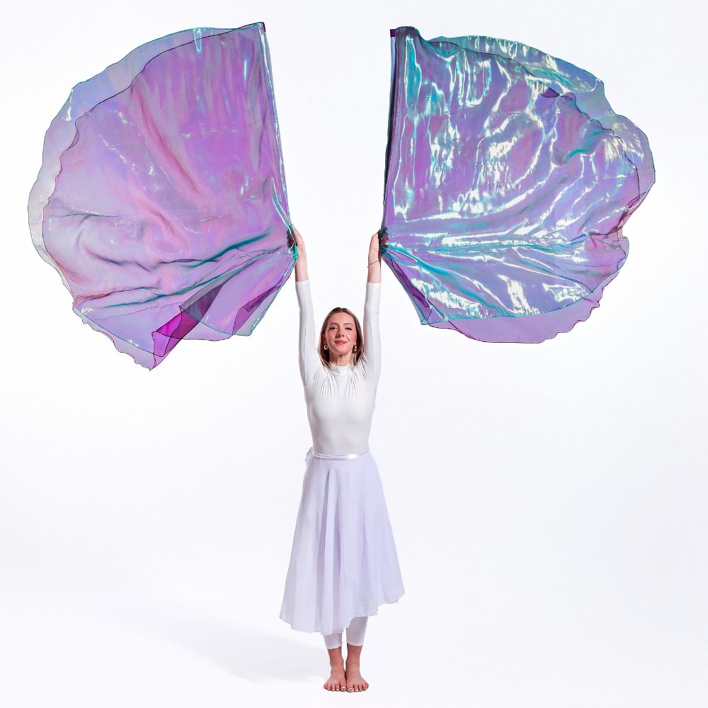 Praise dancer in a white outfit holding Anointed, double-layer large, colorful, iridescent worship wings against a white background in victory dance movement