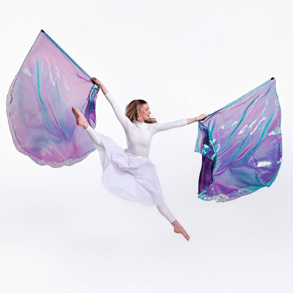 Praise dancer in white praise garments holding Anointed, double-layer large, colorful, iridescent worship wings against a white background