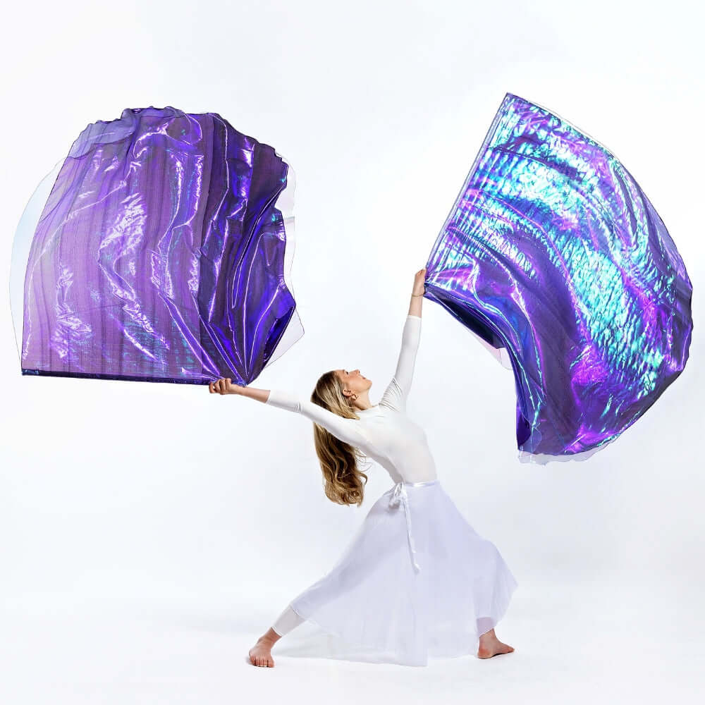 Worship dancer stretches in a powerful pose holding purple metallic and iridescent lilac flags, declaring the worthiness of the King with Casting Crowns worship flags.