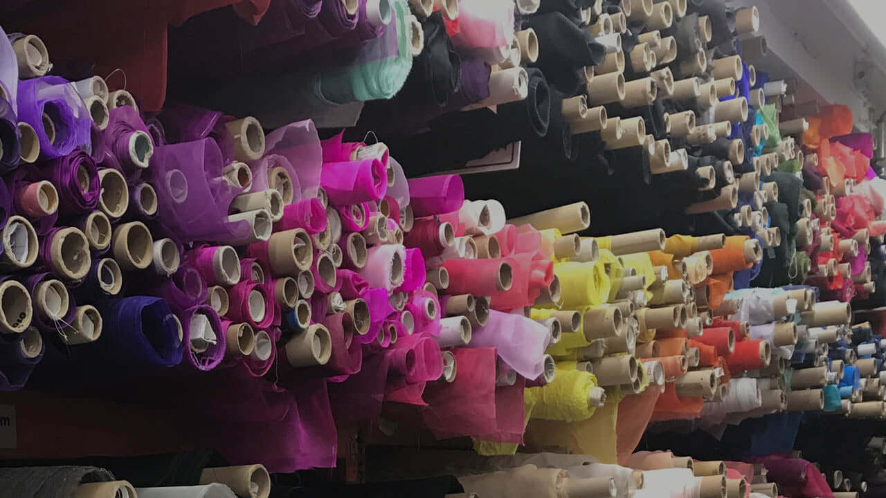 Colorful fabric rolls stacked for worship flag creation — a kaleidoscope of praise waiting to be shaped into movement that glorifies the Lord. Perfect for DIY flag makers at Catch the Fire Worship Flags.