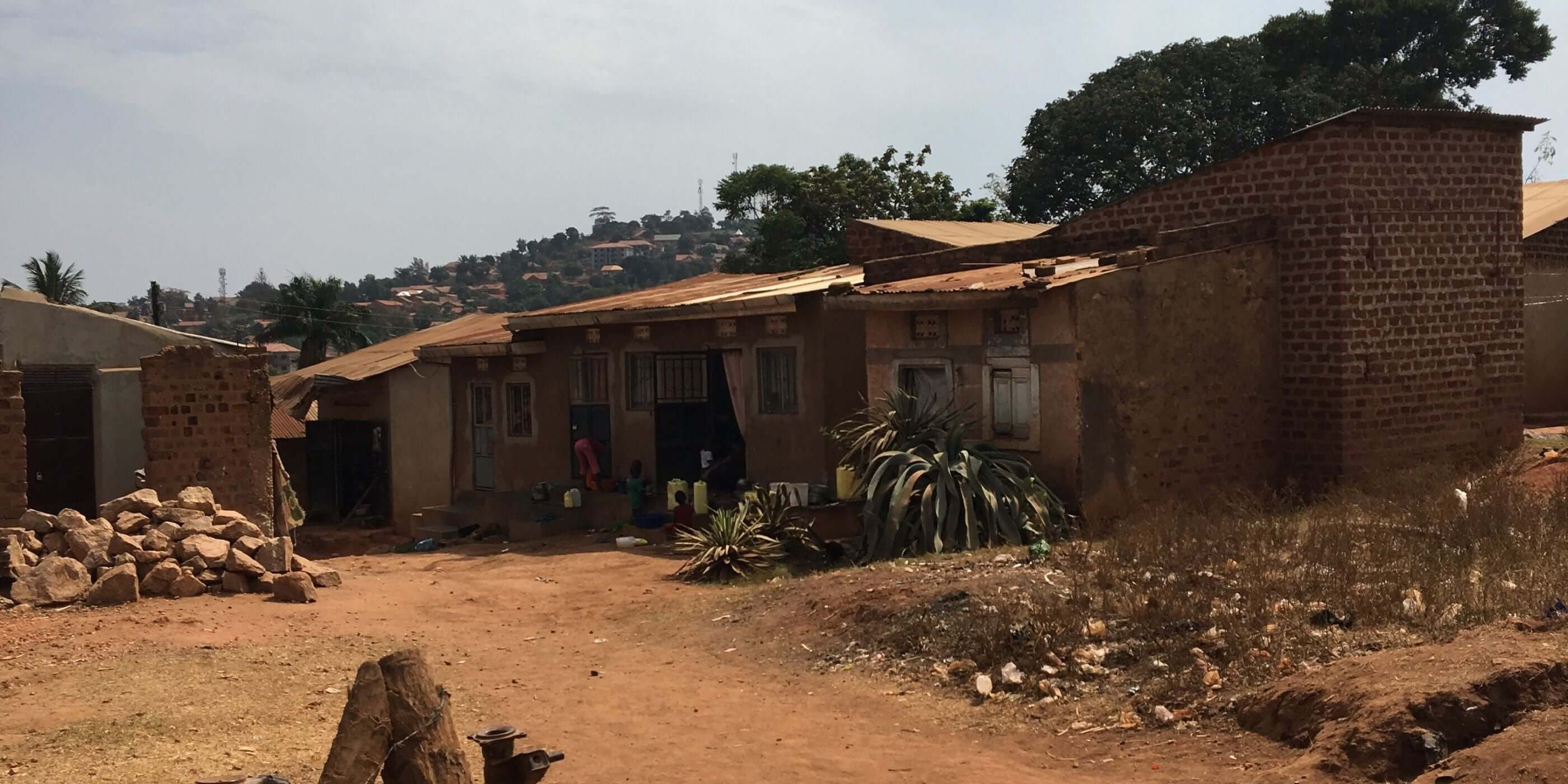 View of a rural neighborhood in East Africa with modest brick homes and red clay roads — representing the mission outreach and charitable giving initiatives supported by Catch the Fire Worship Flags to empower communities through education, provision, and hope.