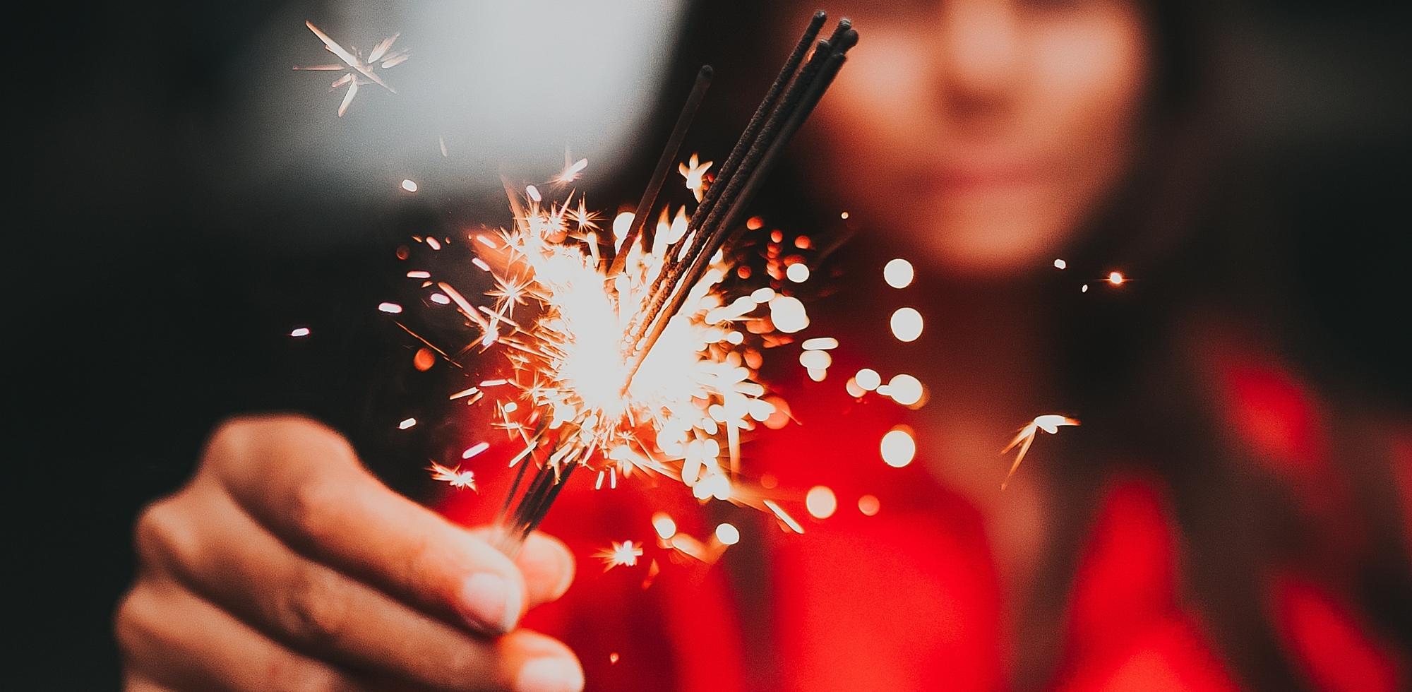 Close-up of hand holding lit sparklers, symbolizing the ignition of worship and the fire of the Holy Spirit — perfect visual for Catch the Fire Worship Flags’ theme of fanning the flame of praise.